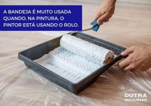 Pessoa usando rolo de pintura em bandeja preta para diluição de tinta.