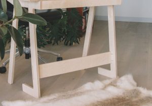 Cavalete de madeira afrente de uma cadeira giratória com rodas