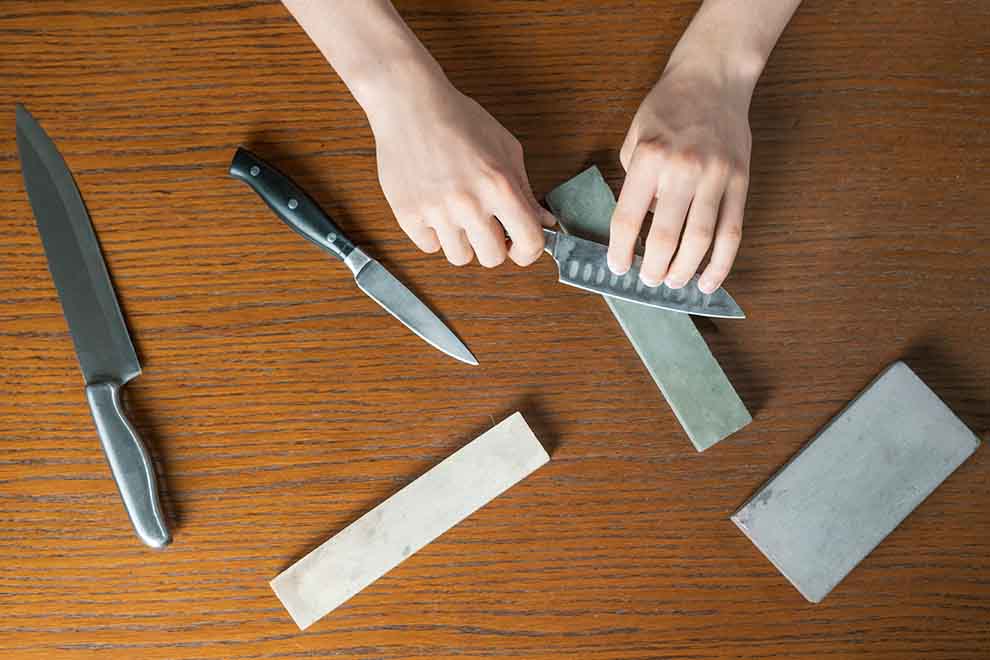 amolar e afiar facas Mãos afiando facas em pedras de afiar