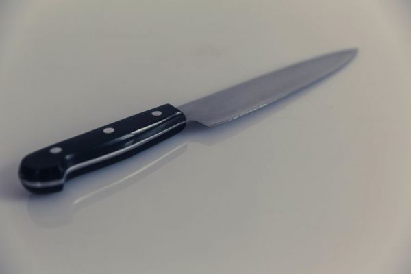 uma faca do cabo escuro, sob uma superfície branca