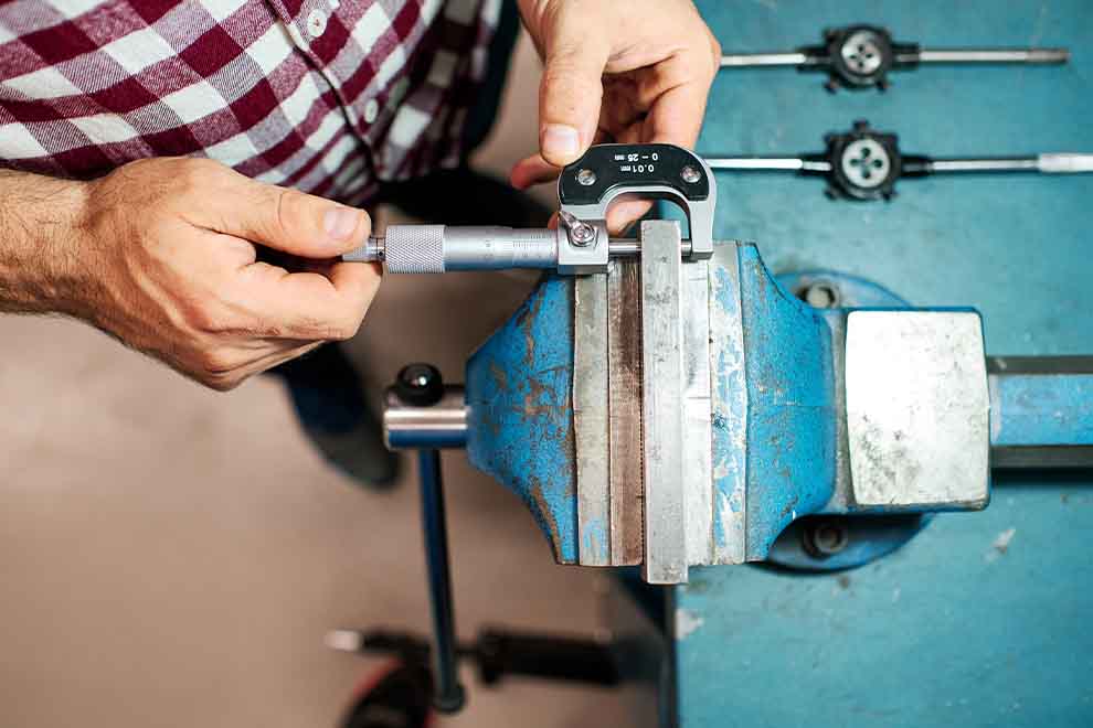 micrometro Homem usando micrômetro em uma bancada de trabalho