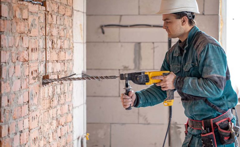 Trabalhador usando furadeira em parede de tijolos
